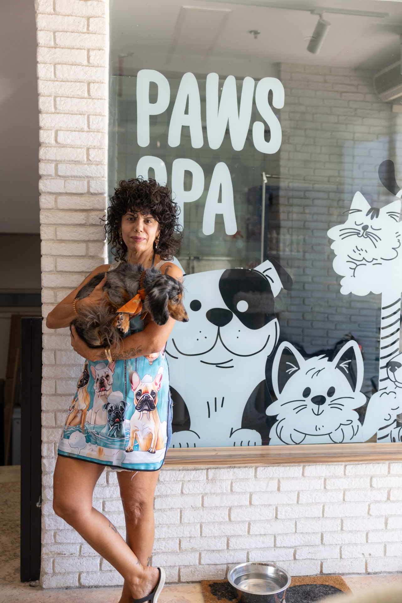 טל, מספרת חיות המחמד, עם כלב בכניסה ל-Paws Spa