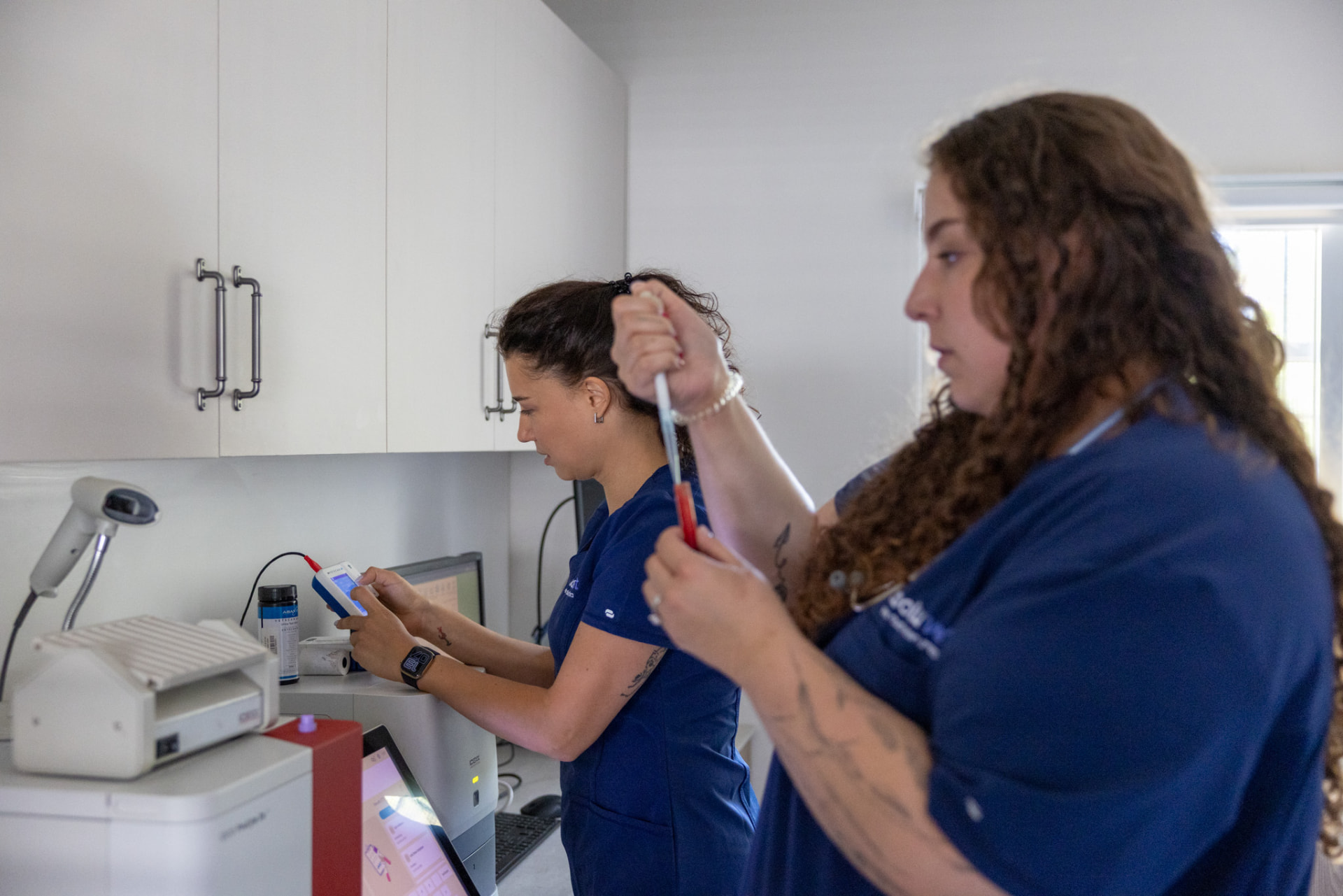 שתי נשות צוות עובדות עם דגימה ומכשור במעבדת המרפאה
